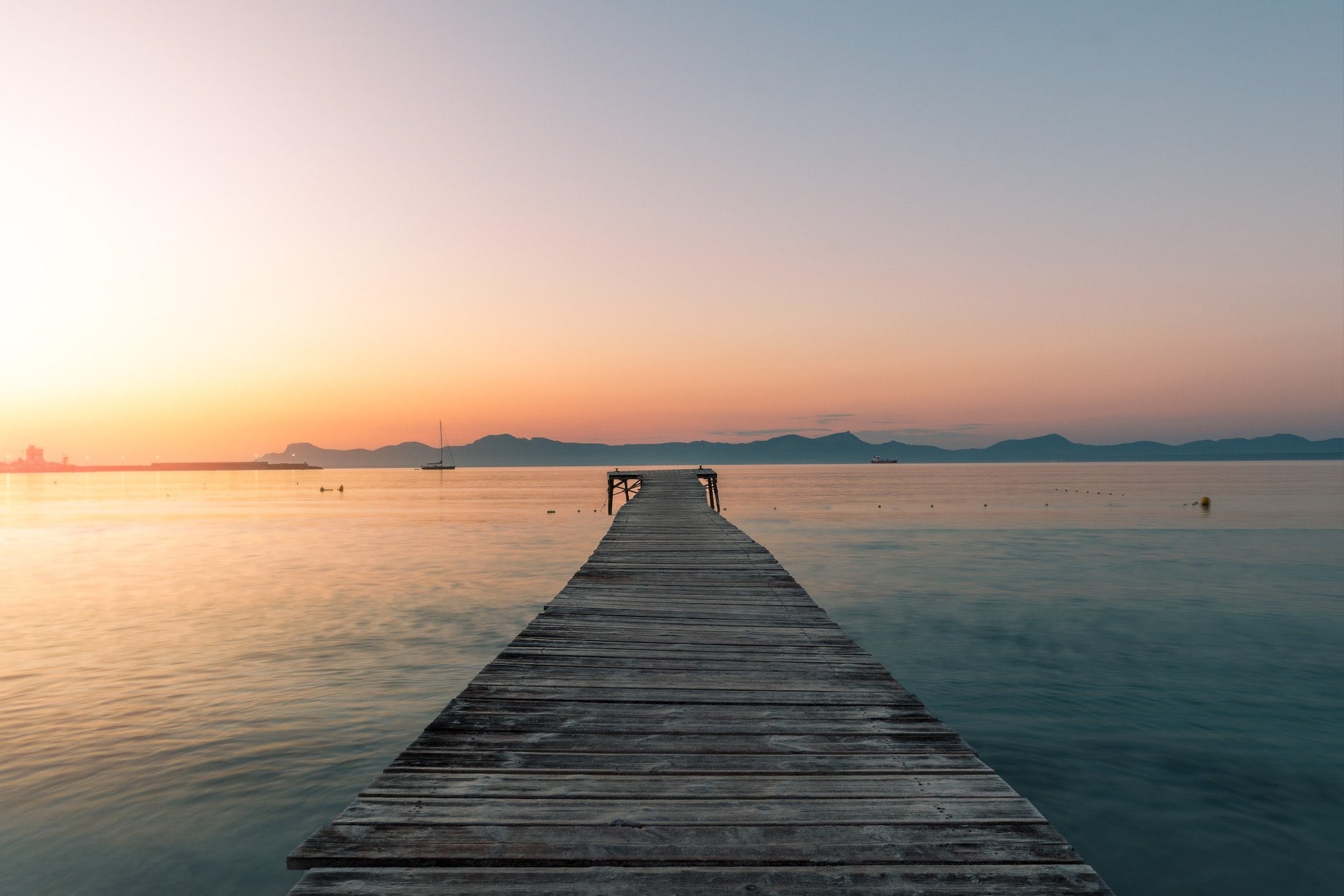 "A minimalist view of the wooden jetty in Alcudia, Mallorca, stretching into the calm Mediterranean Sea under soft morning light. Fine art photography available as a 100% cotton canvas or Limited Edition Giclée print, featuring a 1.5-inch (3.8 cm) solid Latvian pine frame."