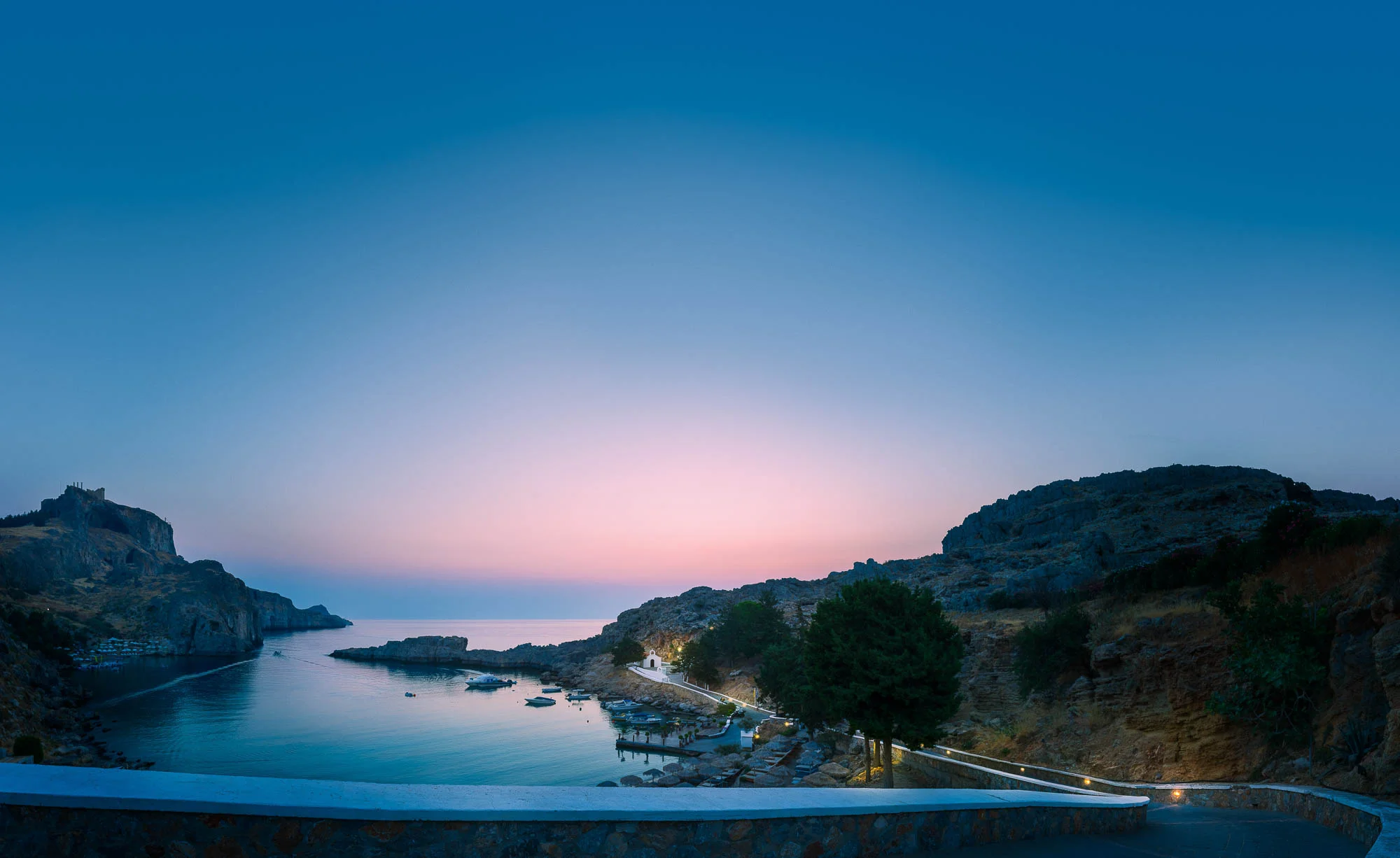 Aeonian Fine Art: First Light St Pauls Bay. Capturing the golden hour essence of the Lindos coastline. Available as a 100% Cotton Canvas on 1.5-inch (3.8 cm) Latvian Pine or as a Limited Edition Hahnemühle Fine Art Print.