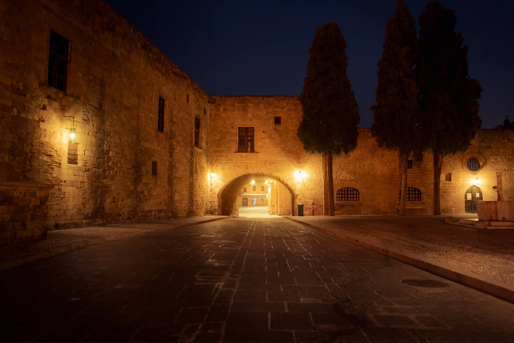 "A moody night-time study of Argirokastrou Square in Rhodes Old Town, capturing the stillness of medieval stone and the ancient fountain under soft streetlighting. Available as a museum-grade 100% cotton canvas or a Limited Edition Giclée print, both mounted on a 1.5-inch (3.8 cm) solid Latvian pine frame."